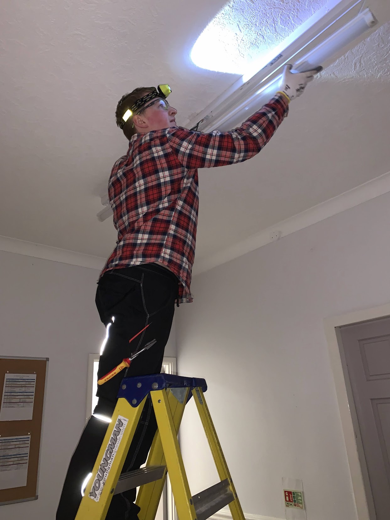 Replacing Light A professional electrician carefully installing an LED downlight in a home
